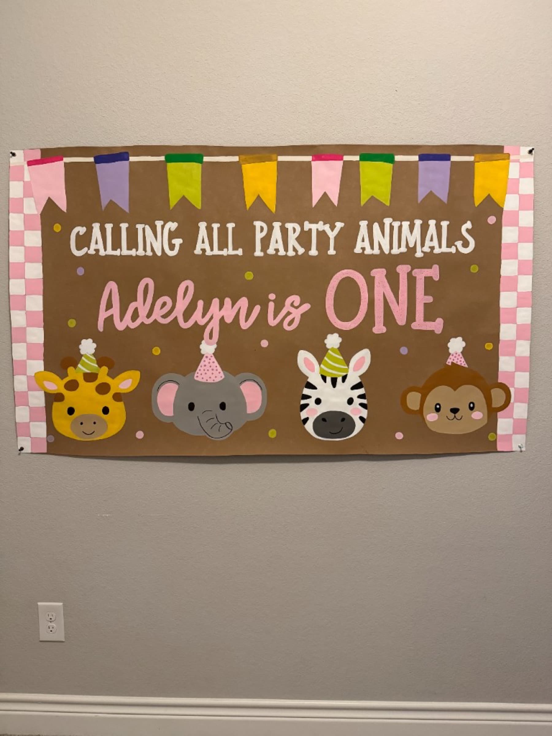 Kraft paper banner reading Calling All Party Animals, Adelyn is One, with a giraffe, elephant, zebra, and monkey in party hats