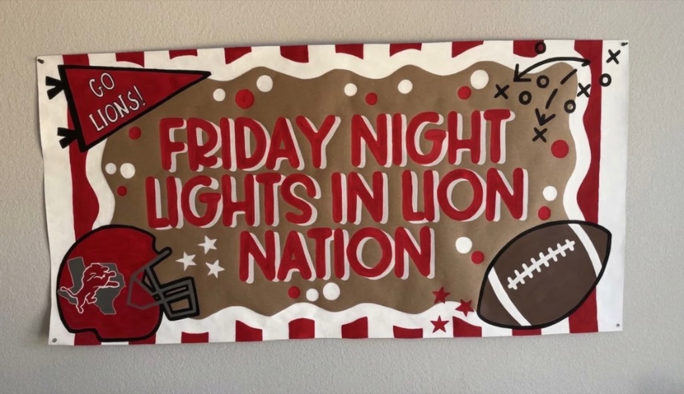 Kraft paper football banner reading Friday Night Lights in Lion Nation with a helmet, football, and red striped borders
