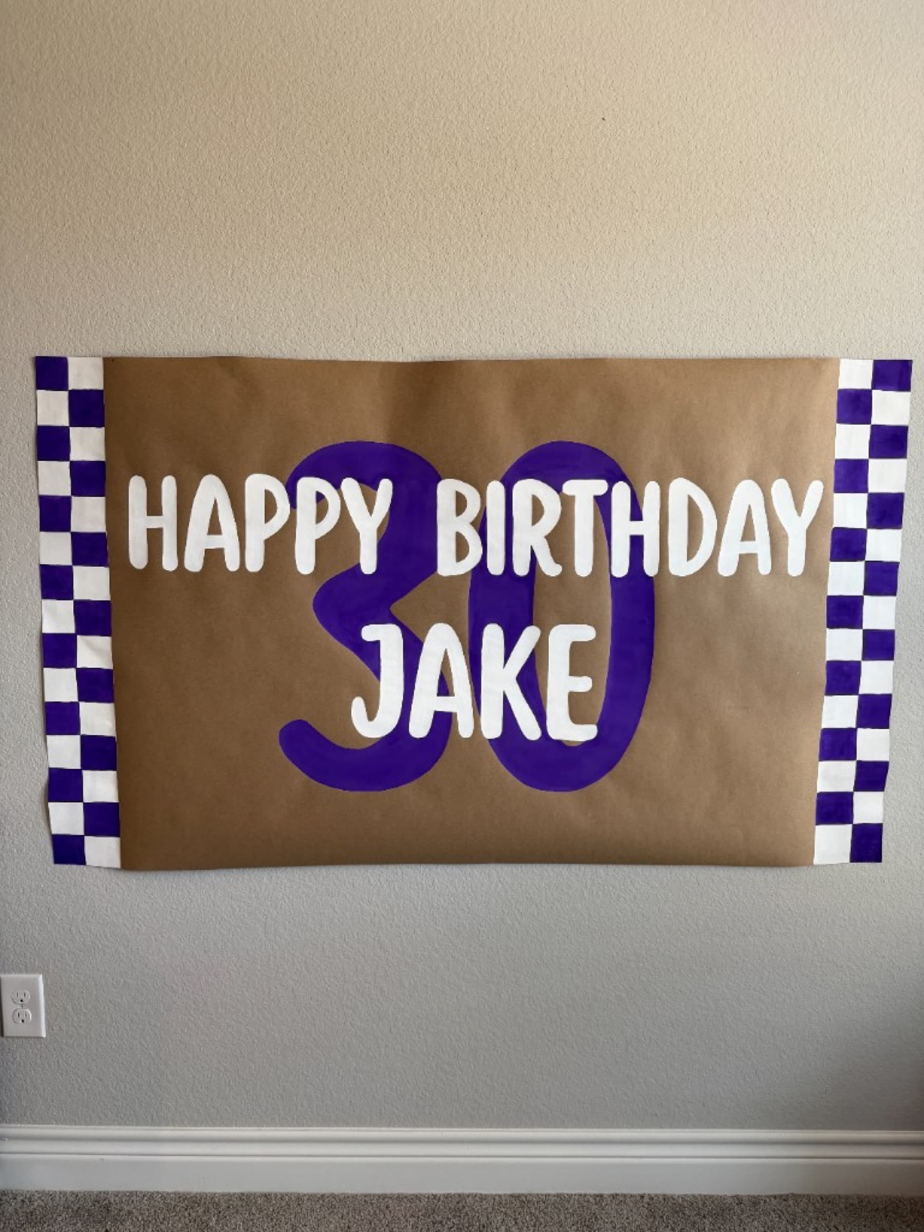 Kraft paper banner reading Happy Birthday Jake with a large purple 30 and purple checkered side borders