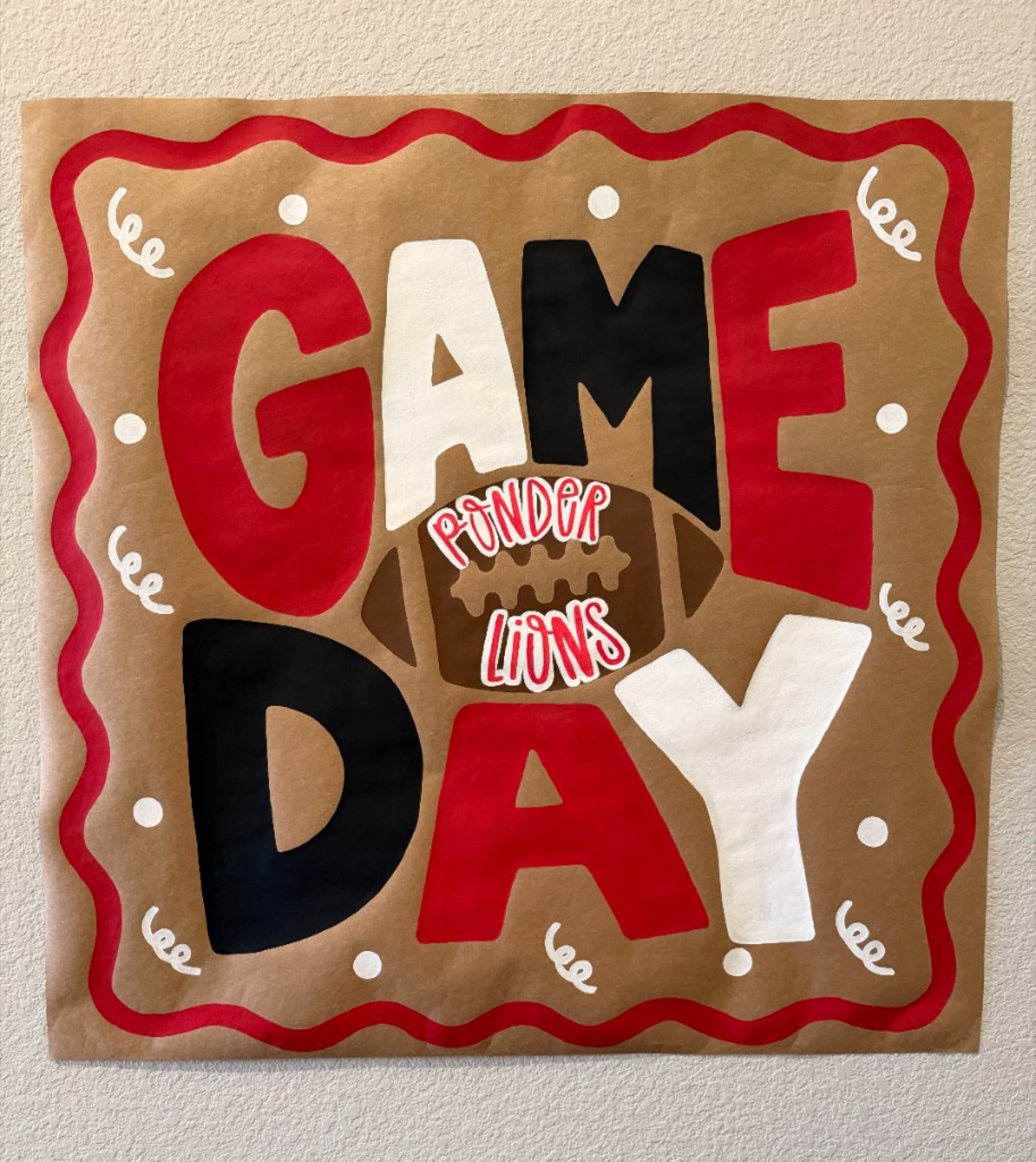 Square Kraft paper banner reading Game Day Ponder Lions with a football in the center and a red wavy border